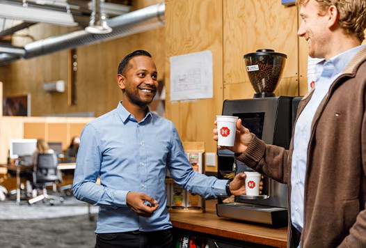 BE - colleagues at a machine with cups