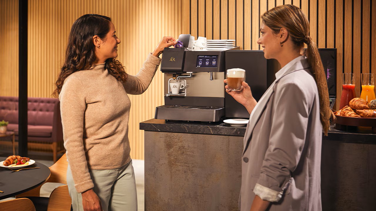 twee vrouwen drinken koffie bij een machine van lor