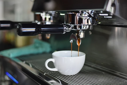 A cup of double espresso coffee under machine